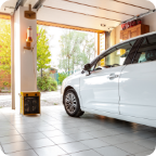 A white car is parked in a bright garage with the door open.  